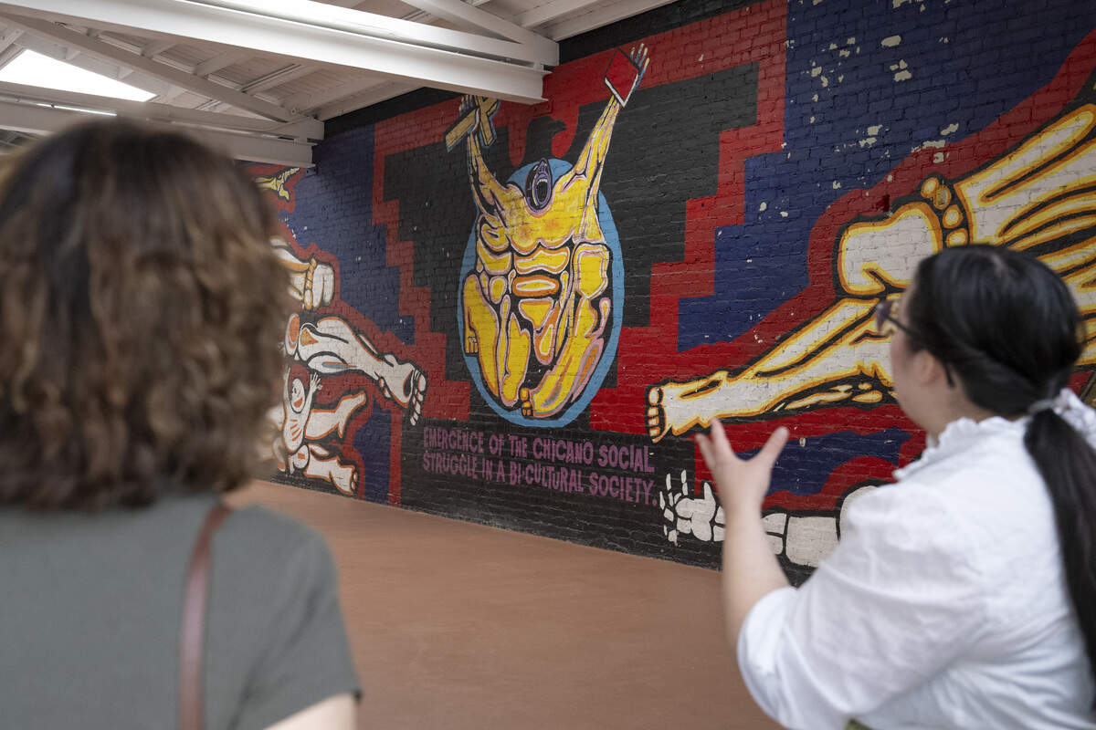 A Preservation Sacramento docent tells visitors about a Royal Chicano Air Force mural inside the Washington Neighborhood Center during Preservation Sacramento’s annual historic home tour in Sacramento on Sunday.